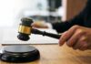 Court Freezes Removal After ICE Gunfire Judge's hand holding a gavel over a sound block