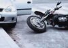 Motorcycle lying on the street beside a car with an open door