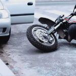 Motorcycle lying on the street beside a car with an open door