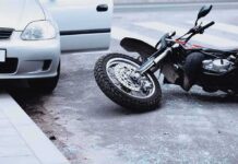 Motorcycle lying on the street beside a car with an open door