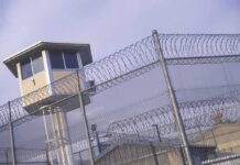 Prison watchtower behind barbed wire fencing