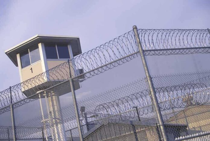 Prison watchtower behind barbed wire fencing