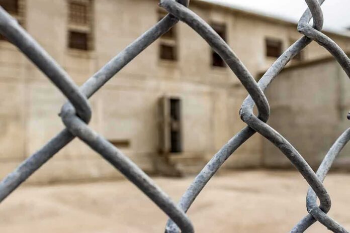 shutterstock_1129781825 Chain-link fence with blurred concrete building behind