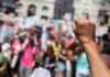 Chant Wars Erupt At UCLA Raised fist in foreground at a crowded street protest
