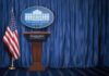 New Trump Bulldog Takes The Mic White House press briefing podium with U.S. flag and blue curtain