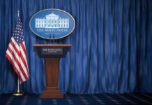 New Trump Bulldog Takes The Mic White House press briefing podium with U.S. flag and blue curtain