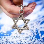 Hand holding a metal Star of David pendant