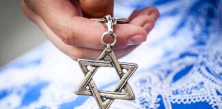 Hand holding a metal Star of David pendant