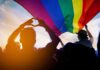 Capitol Clash Brewing Over Trans Bill Crowd under a rainbow flag at sunset
