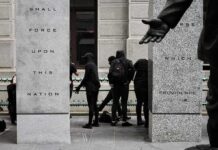 Masked Raiders Hit City Hall group of masked people in black clothing between granite pillars