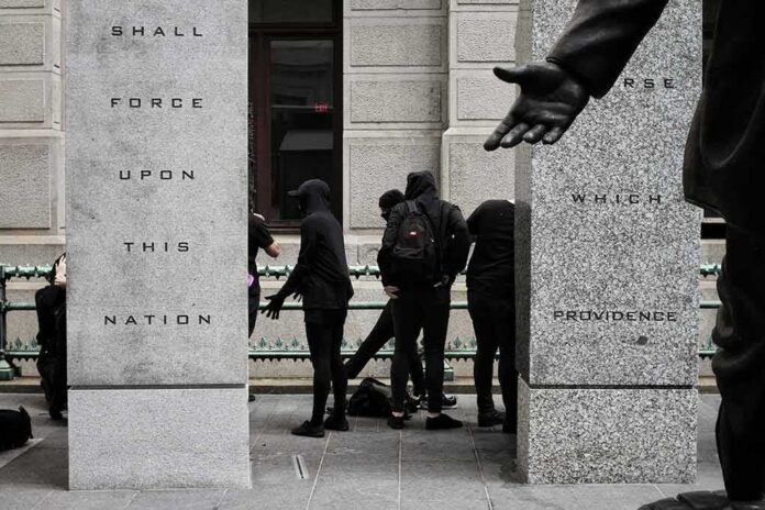 shutterstock_1189147324 group of masked people in black clothing between granite pillars