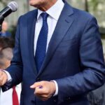 Man in a navy suit speaking at a microphone