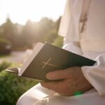 Vatican Rush: Pope Heads Into Surgery Person in white robe holding a Bible outdoors