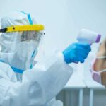 Quarantines Over One Broken Vial Healthcare worker in PPE checks patient temperature with infrared thermometer