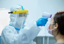 Quarantines Over One Broken Vial Healthcare worker in PPE checks patient temperature with infrared thermometer