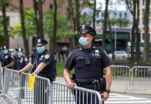 Walter Jones, a police officer in a face mask standing by metal barricades