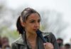 Affluent Suburb Twist In AOC Story AOC speaking into a handheld microphone outdoors