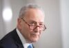 Schumer Puts Tariffs At Center Of Debate older man in suit with red glasses looking to the side