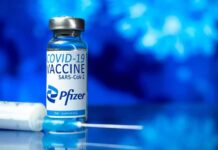 Pfizer COVID-19 vaccine vial with syringe on blue background