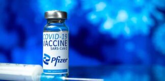 Pfizer COVID-19 vaccine vial with syringe on blue background