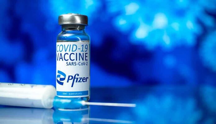 Pfizer COVID-19 vaccine vial with syringe on blue background