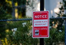 Police Dragnet Nails Wrong Driver? Red notice sign on a black pole in a leafy outdoor area