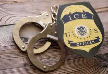 Mayor Slams Raids After Car Shooting ICE officer badge and handcuffs on wooden surface