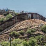 Livestock Loophole Fuels Smuggling Border fence running over a hilly landscape