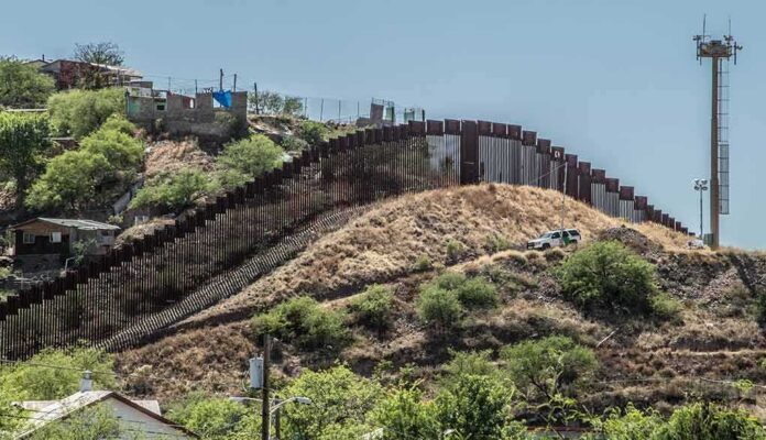shutterstock_464574014 Border fence running over a hilly landscape