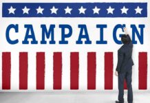 Flu Or Psych Ward? Timeline Doesn’t Add Up Man in suit writing on large campaign banner with stars and stripes