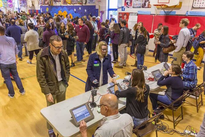 Don MacLean in a busy gymnasium voting station with check-in tables