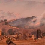 Evacuations Explode Across Orange County Wildfire burns on hillside near suburban homes