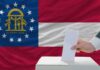 Atlanta Chaos Returns With A Vengeance Georgia state flag with a hand casting a ballot